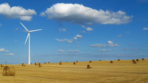 Une éolienne installée dans un champ avec des bottes de paille