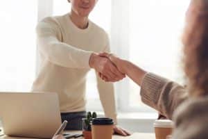 jeune homme debout qui serre la main d'une personne assise en face de lui